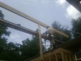 Carpenter setting a ridge beam over a new addition frame — Ice Dam Removal by Roofing Brothers in Falls