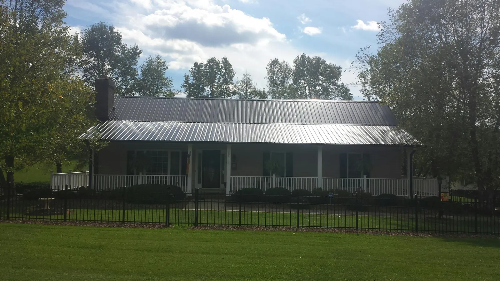 Gray metal roof on a brick ranch with a full width front porch — Gutter Guard Installation work by our crew in Falls