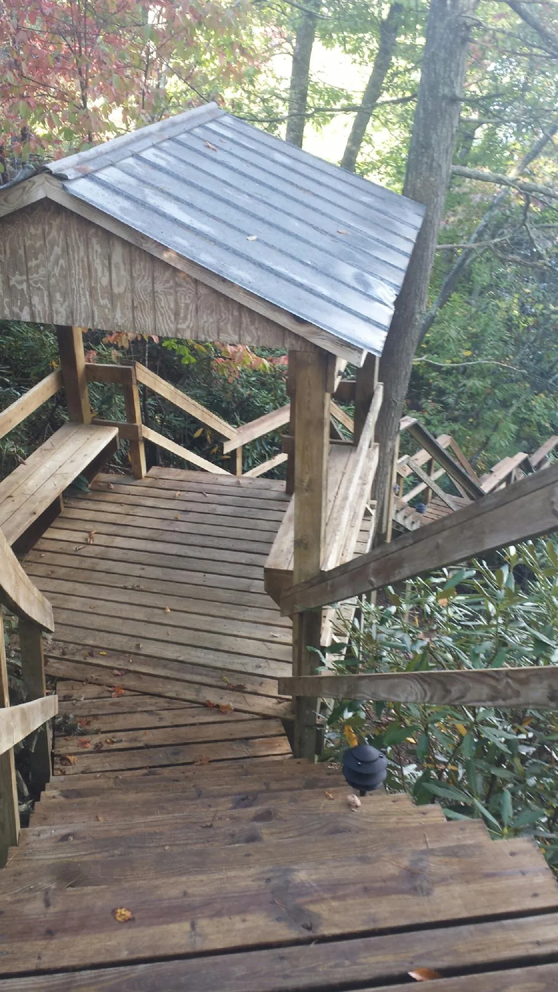Metal roofed shelter over wooden steps on a wooded walkway — Skylight Repair & Installation work by our crew in Falls
